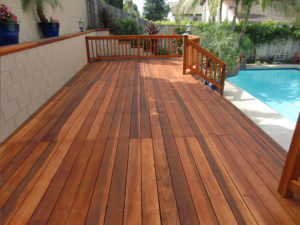 A nicely finished and protected redwood deck bordering a family swimming pool.