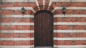 oak front door set in a multicolored brick home