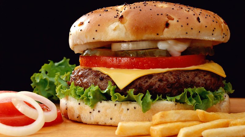 Cheeseburger with onions, mayonnaise, pickles, lettuce, and tomatoes