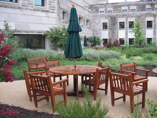 A teak table set with umbrella sitting in an outdoor patio area
