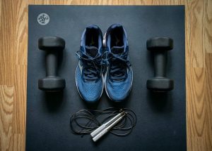 A pair of tennis shoes and hand weights and a jump rope sitting on a mat in a gym