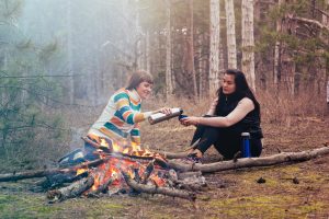 two women sitting in front of a camp fire