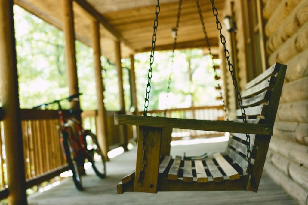 Wooden swing on the front porch of a wooden cabin