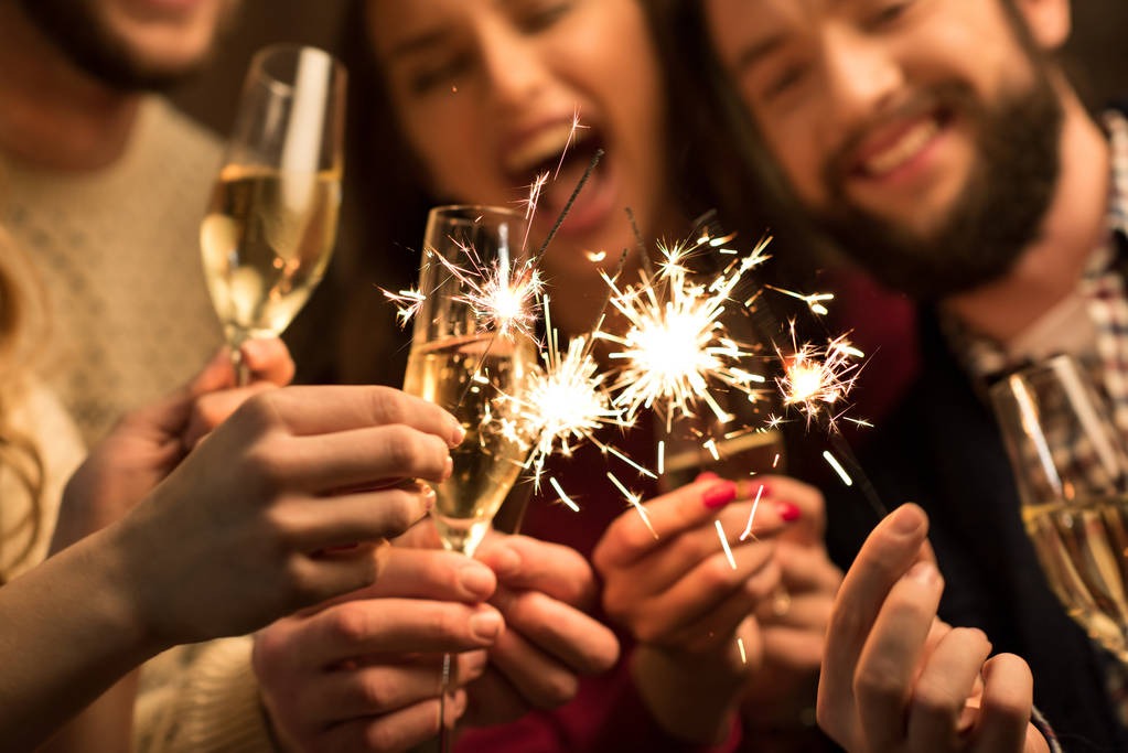 People holding glasses of champagne and sparklers at a New Years party