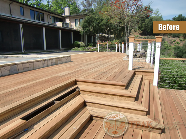 A weather-beaten cedar deck with planks missing on a lovely home bordering a stone-trimmed pool.